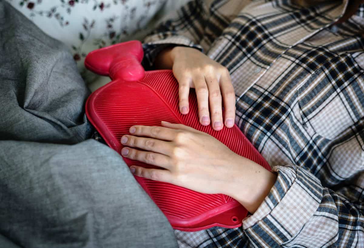 person holding a red hot water bag