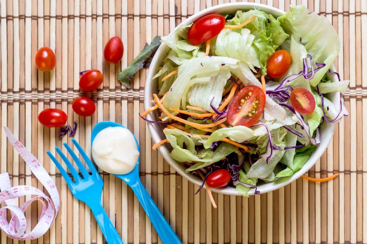 Dietary salad with fresh vegetables (tomato, cucumber, Chinese cabbage, red onion and cranberries). Top view wood backgtound