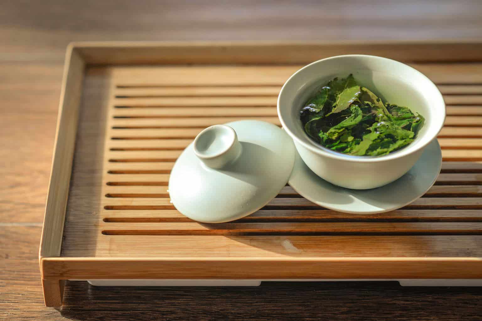 one of weight loss drink: green tea leaves in white ceramic bowl with open lid
