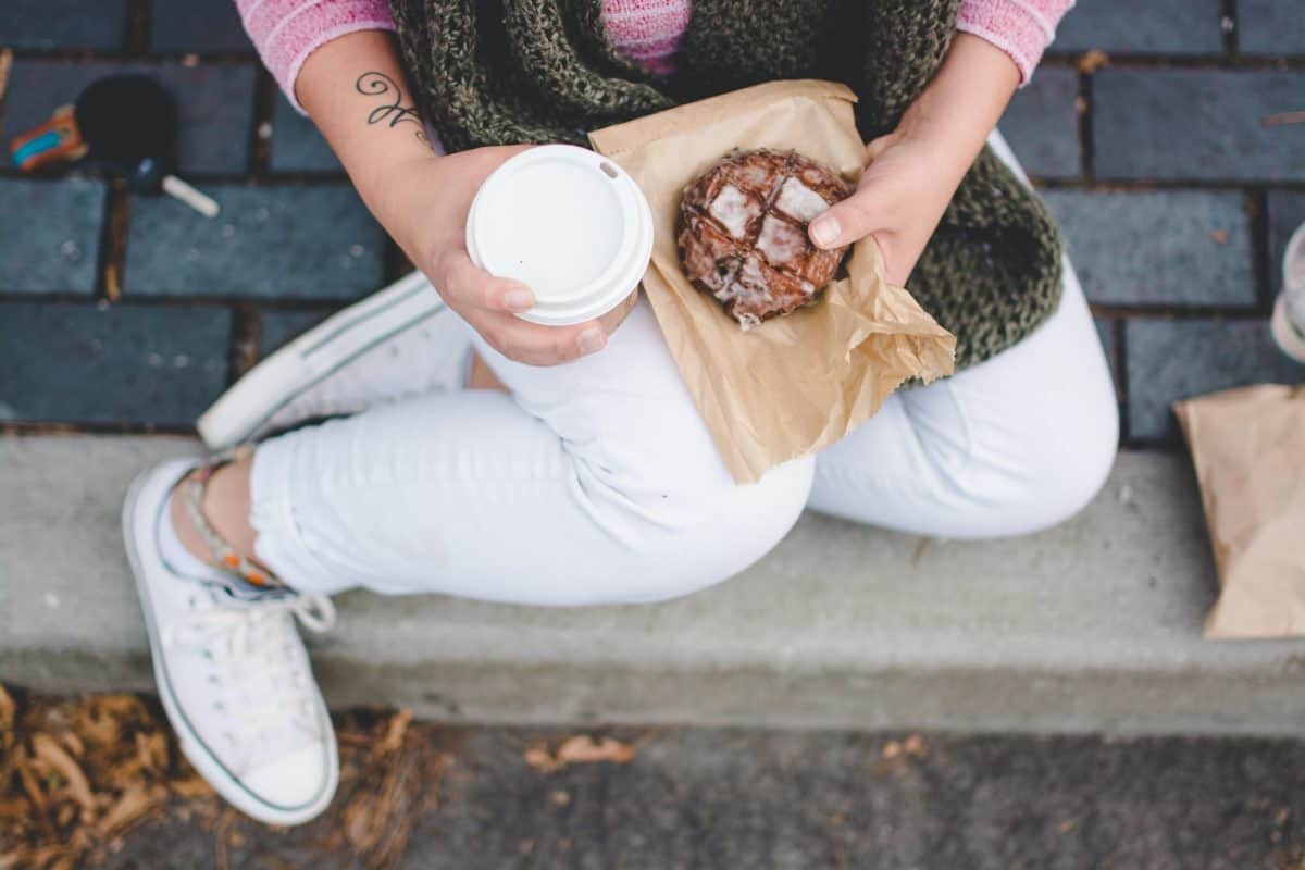 a person sitting while holding a cup of coffee and a cookie
