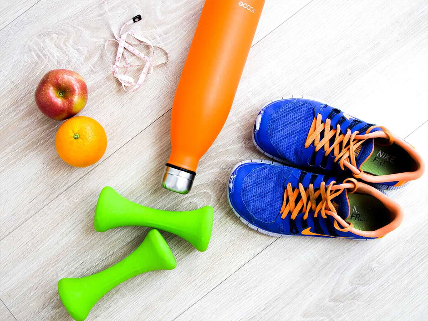 things that you need for diet and exercise; sneakers, dumbells, apples, and a bottle of juice