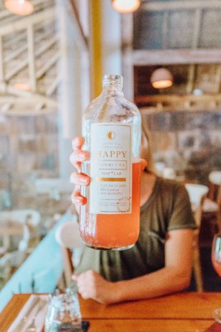 Woman holding up a bottle of kombucha