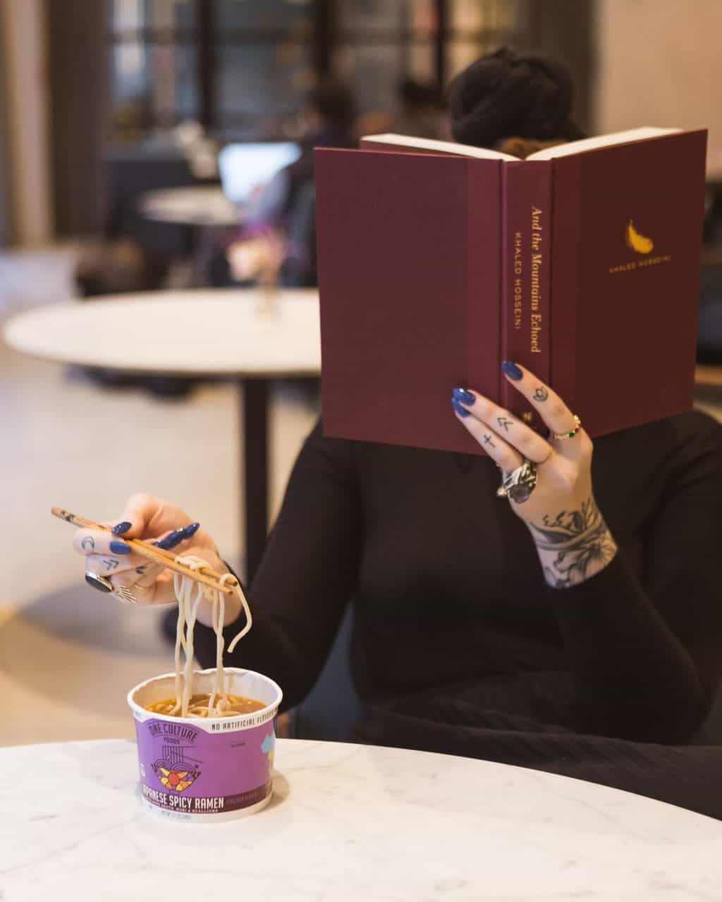 woman eating behind a book